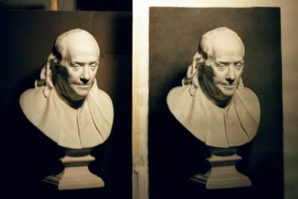 A photo of a fully rendered charcoal drawing done with the sight size method, side by side with a plaster cast. 