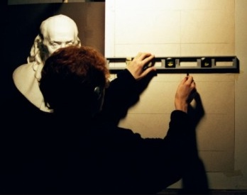 A photograph of an artist using a ruler to draw lines and using the sight size method.